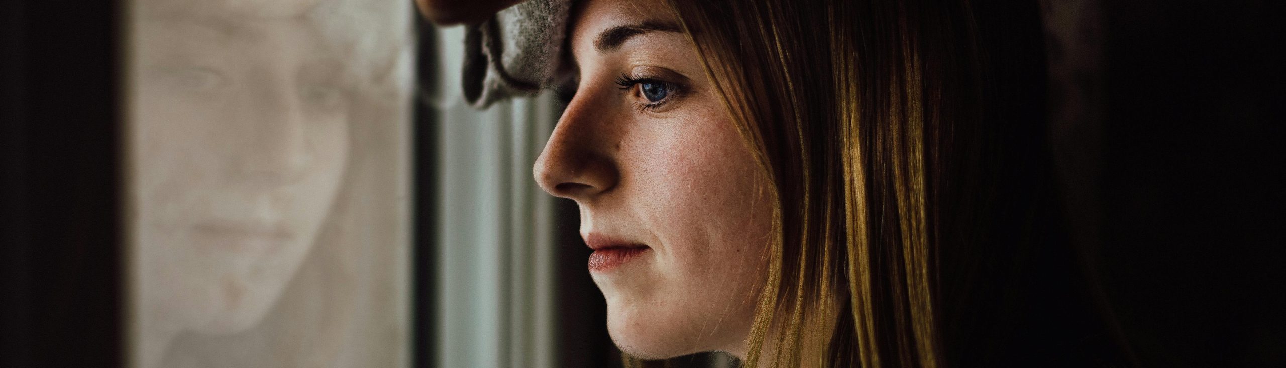 Woman gazing out window contemplating thinking finances